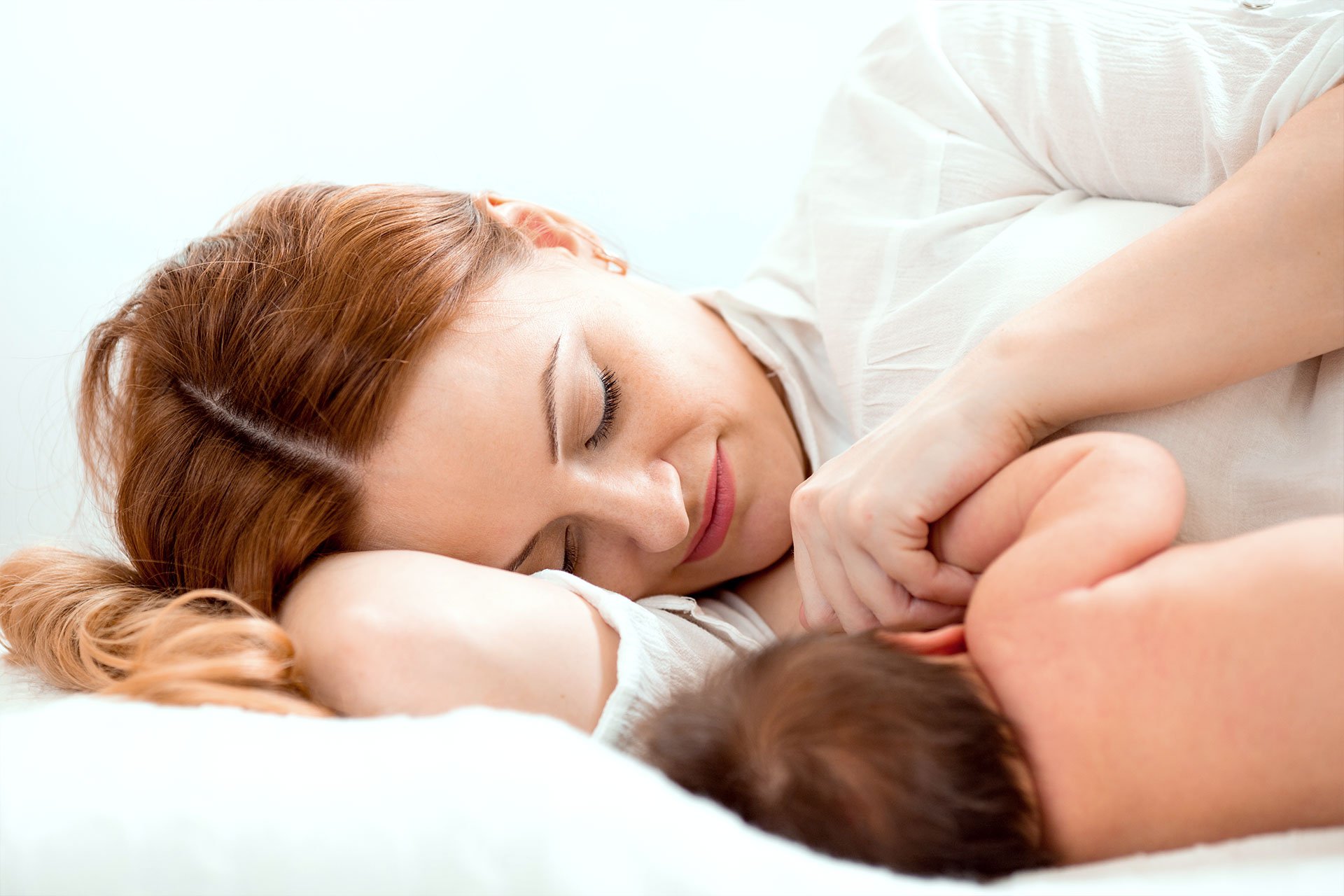 Mamá acostada con su bebé recién nacido