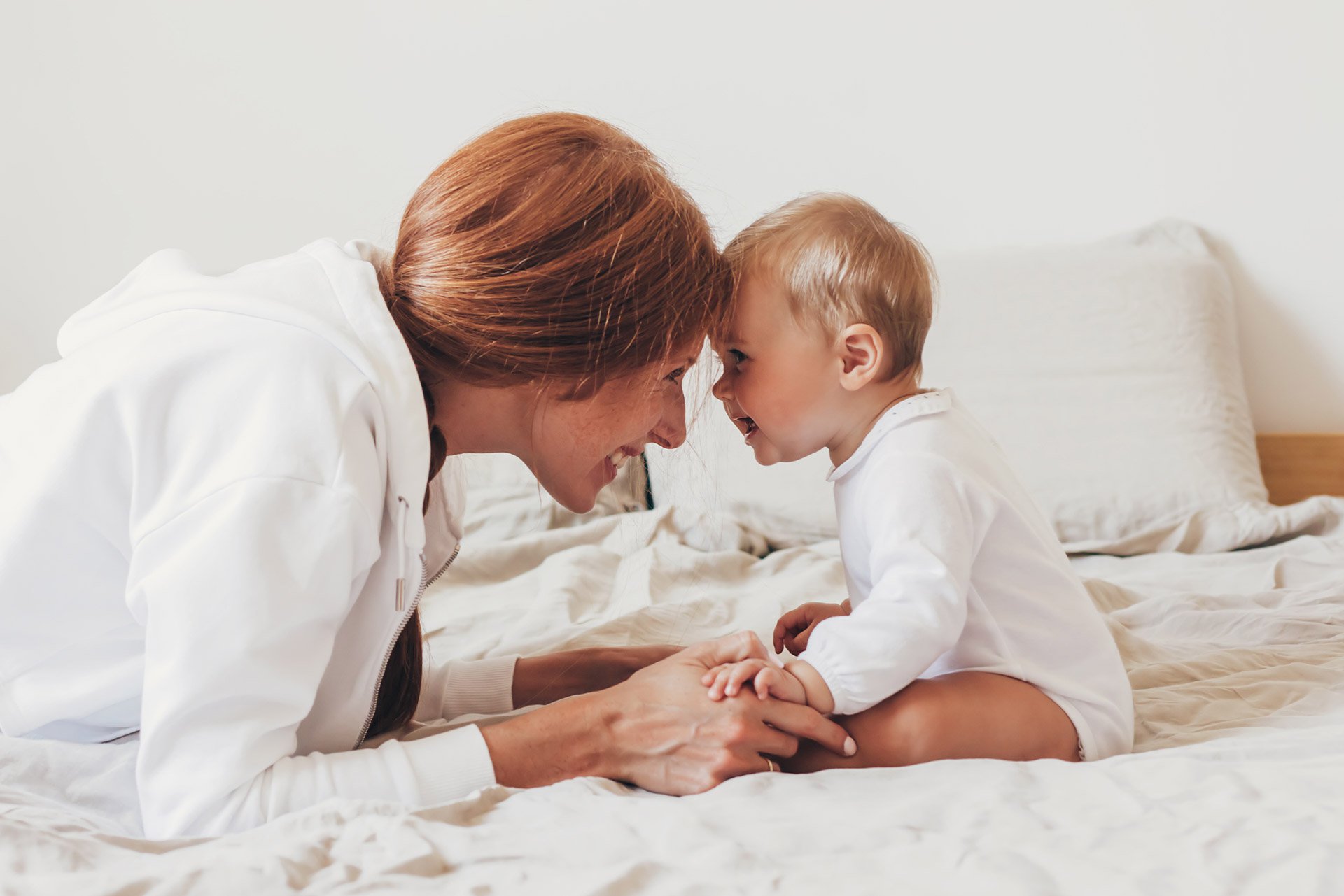 Mamá sonriéndole a su bebé en la cama
