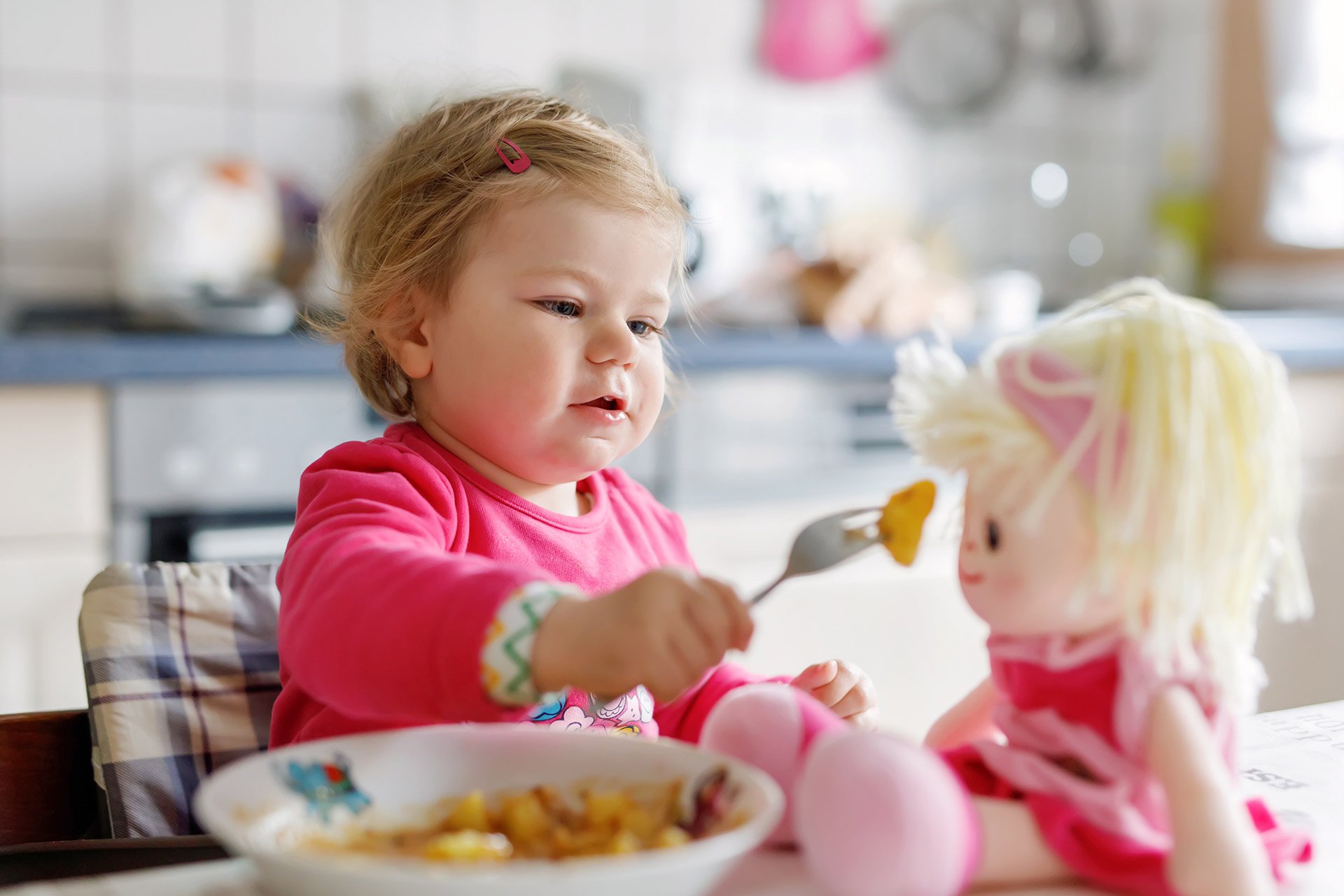 Bebé jugando con su muñeca a comer