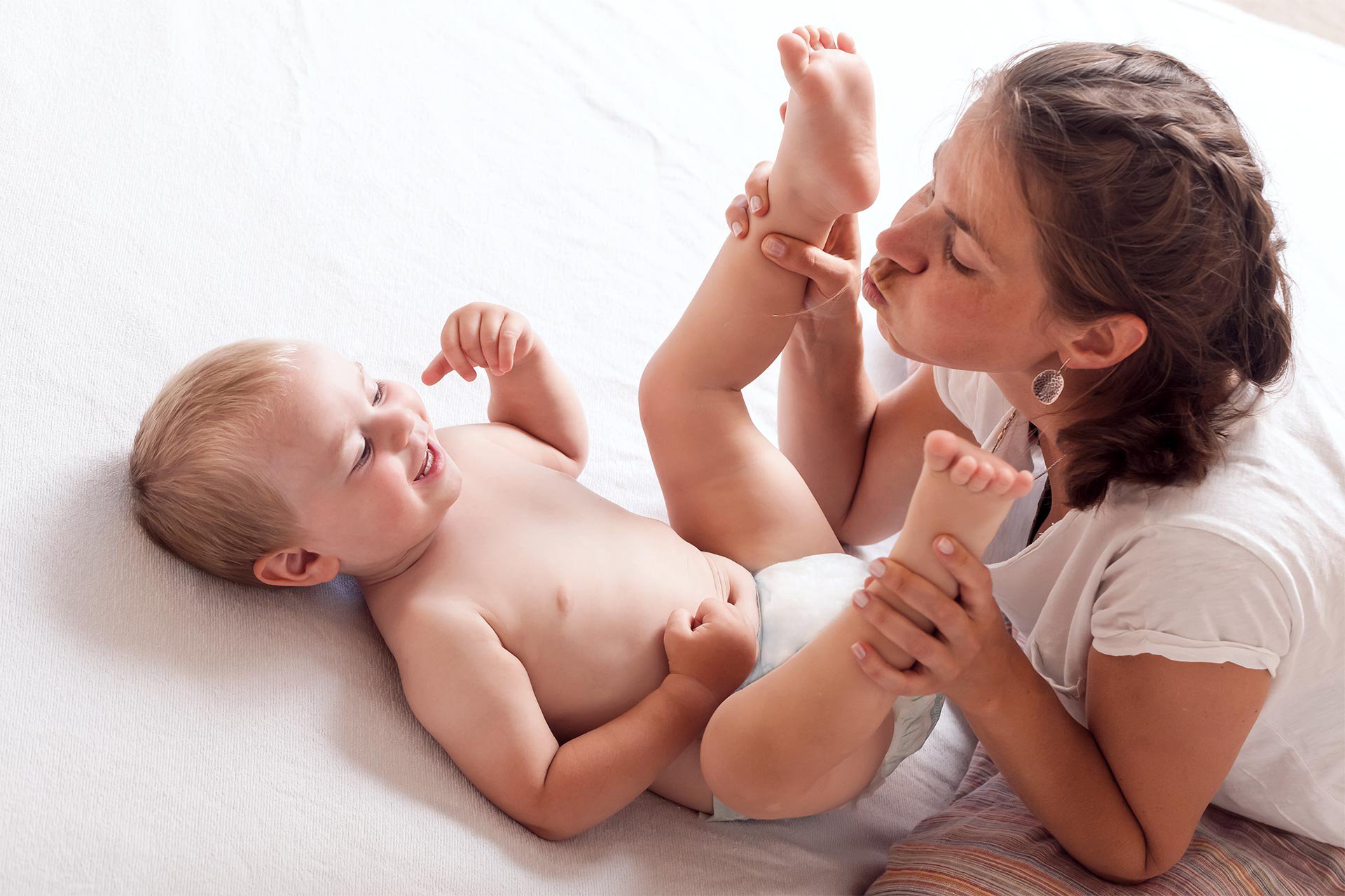 Mamá jugando con su bebé en la cama