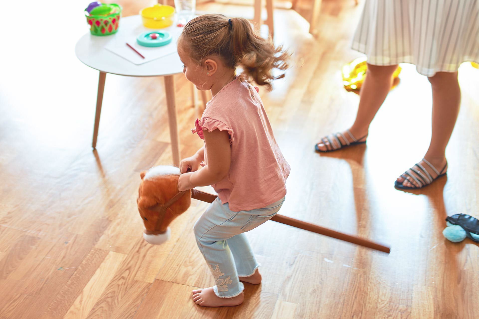 Niña jugando con caballito de palo