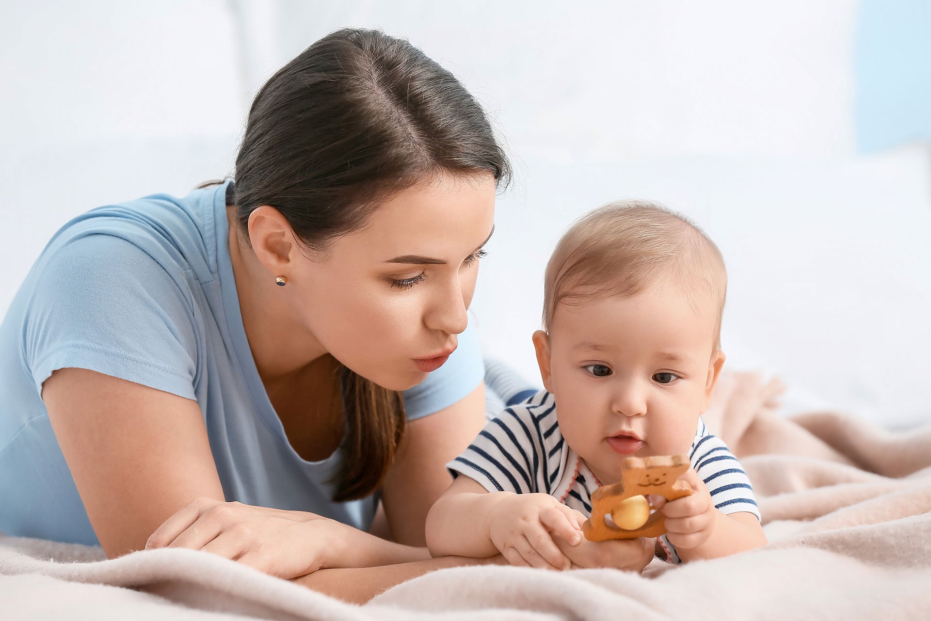 Mamá jugando con su bebé en la cama
