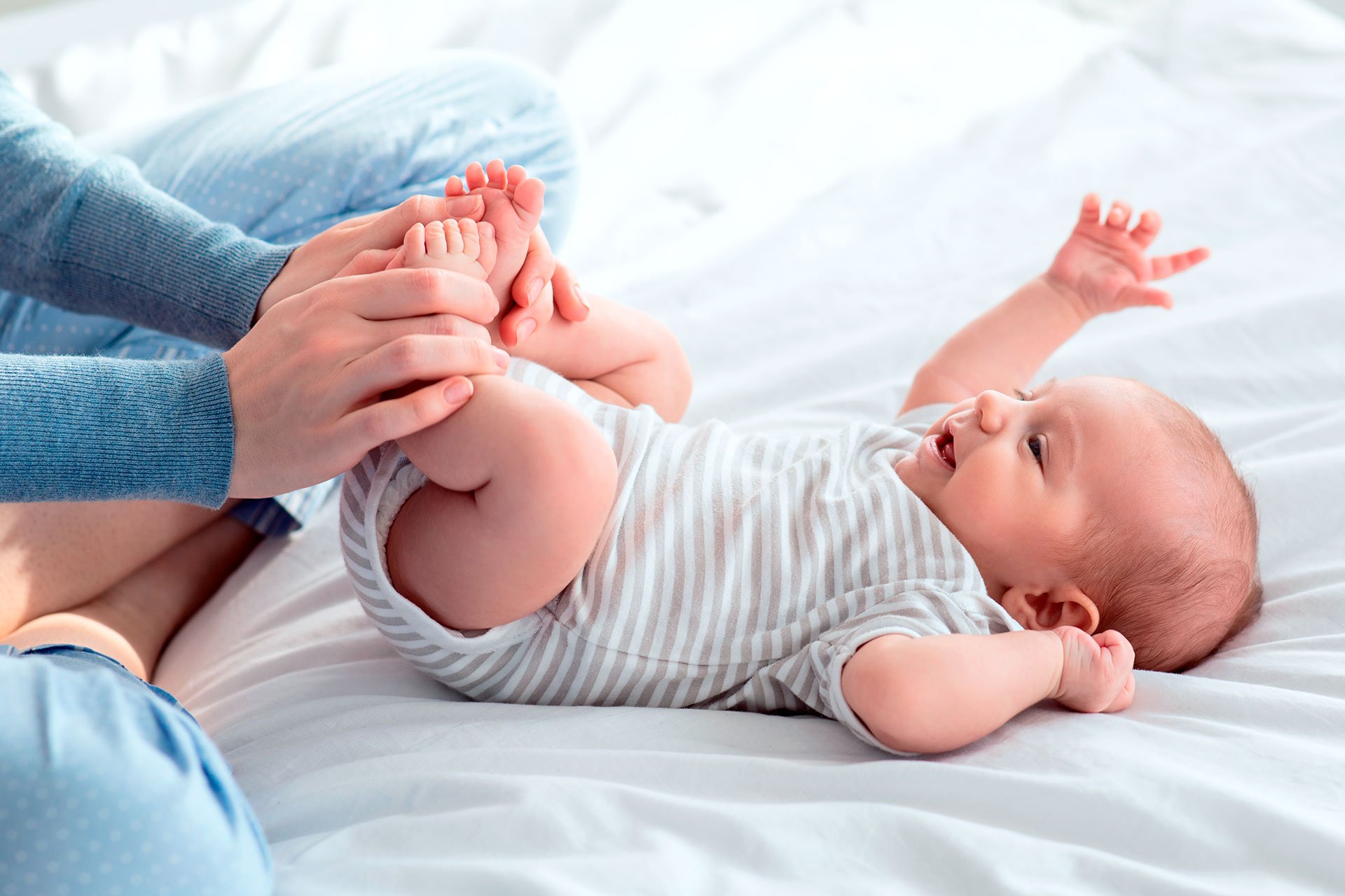 Bebé juega con su mamá en la cama