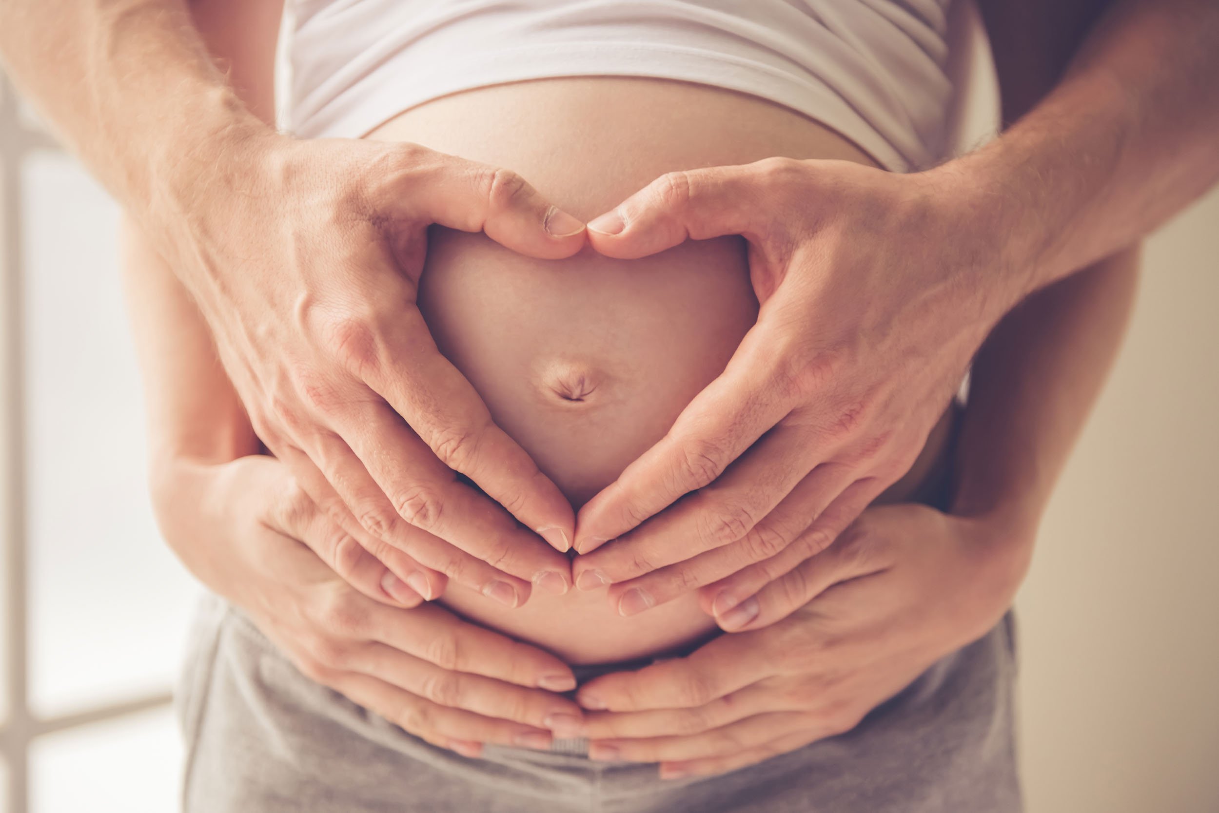 Papás formando un corazón en barriga embarazada