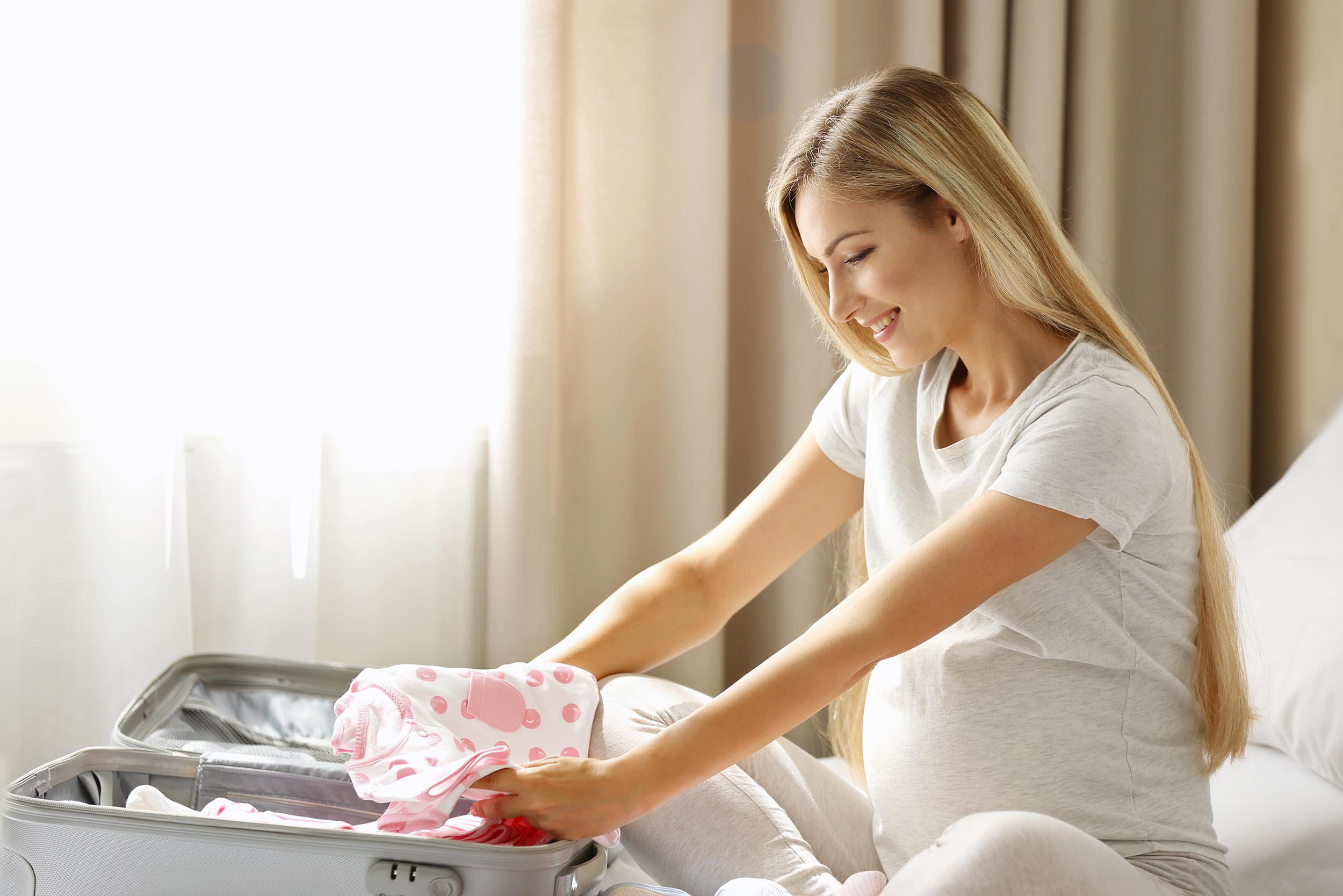 Mamá guardando ropa de bebé en una maleta