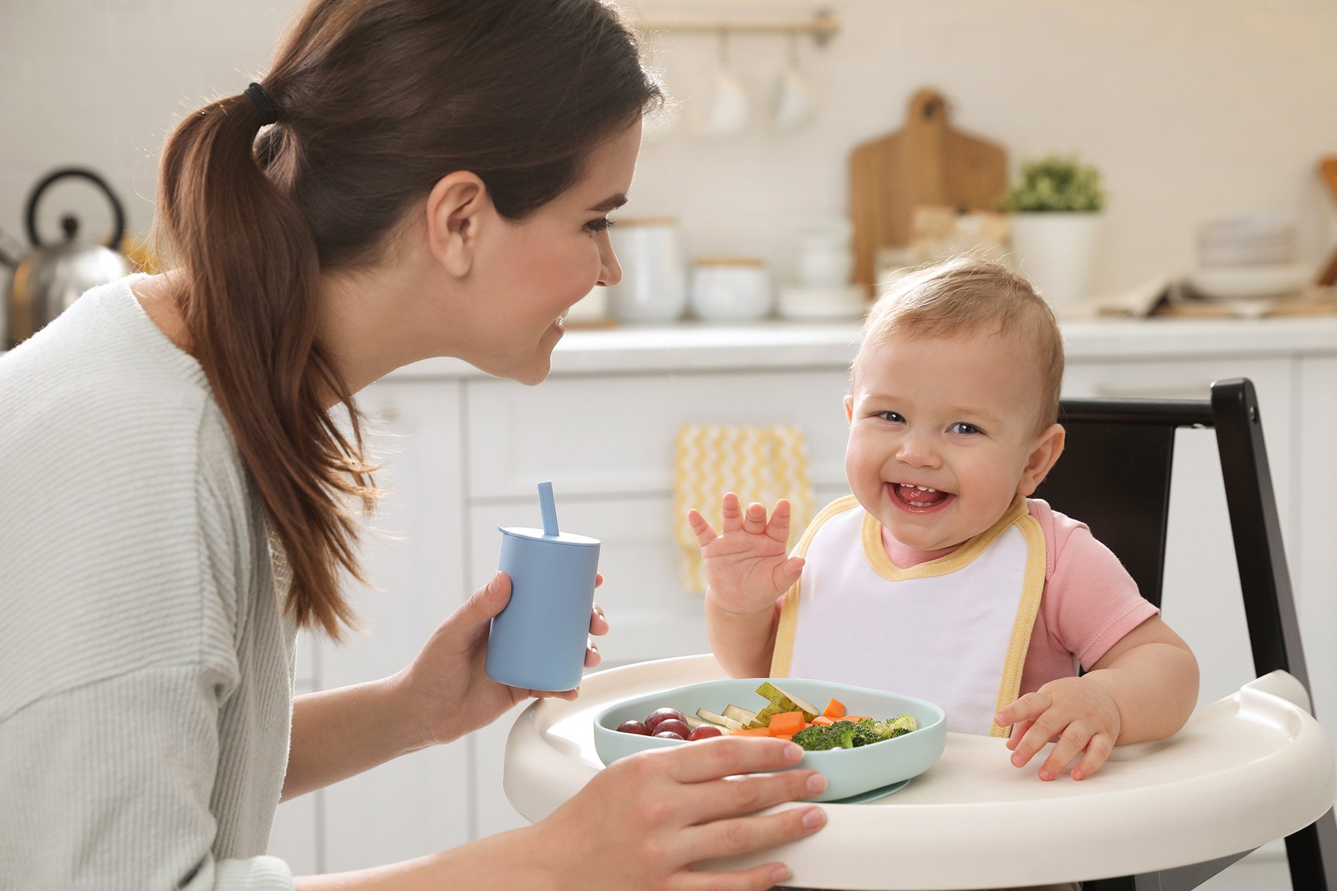 Bebé feliz comiendo con su mamá