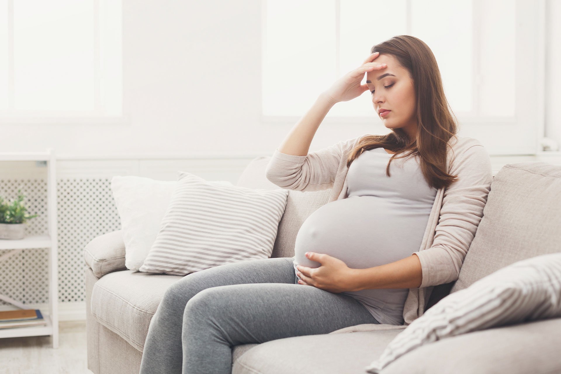 Mujer en sofa con dolor de cabeza