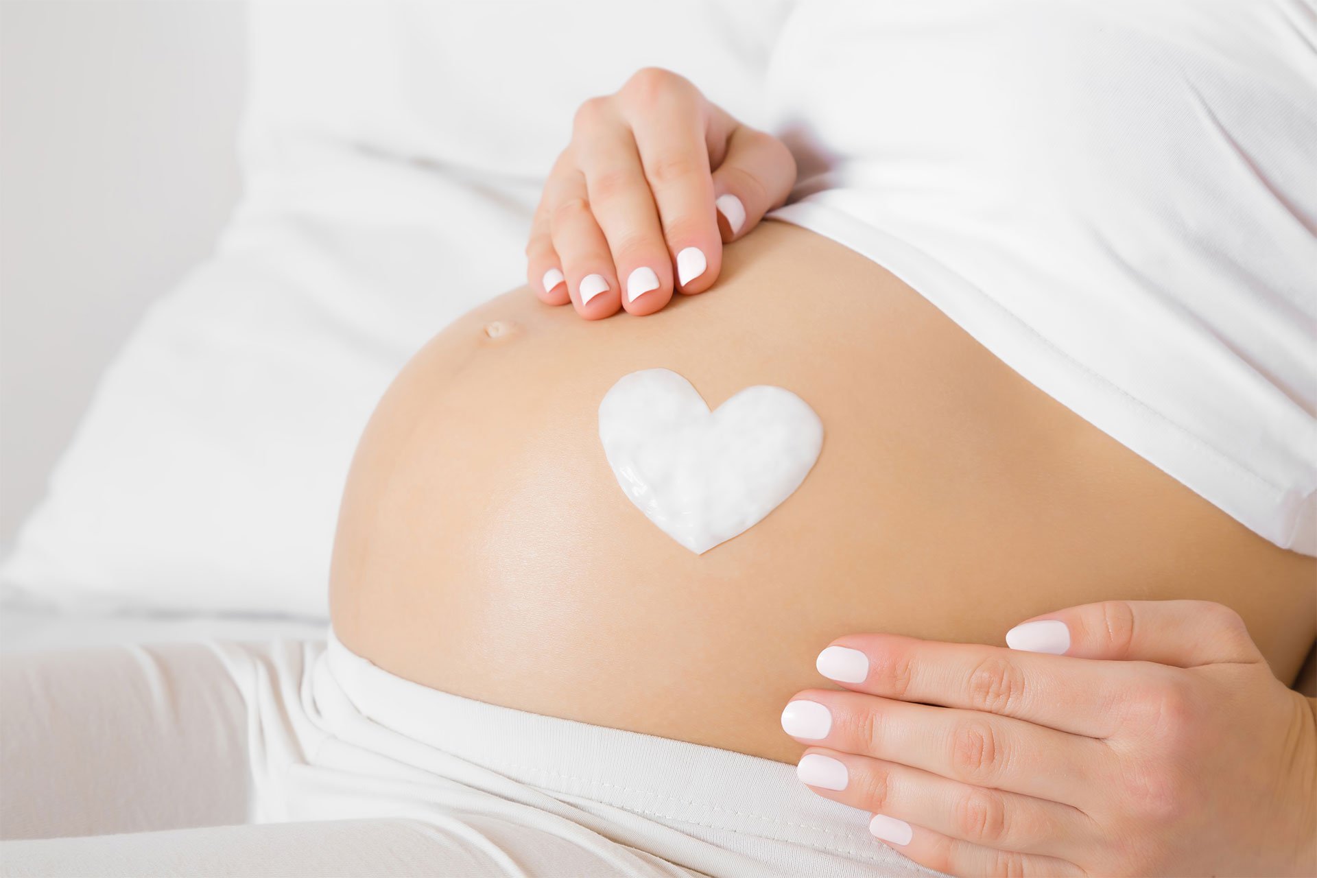 Corazón de crema en barriga de embarazada