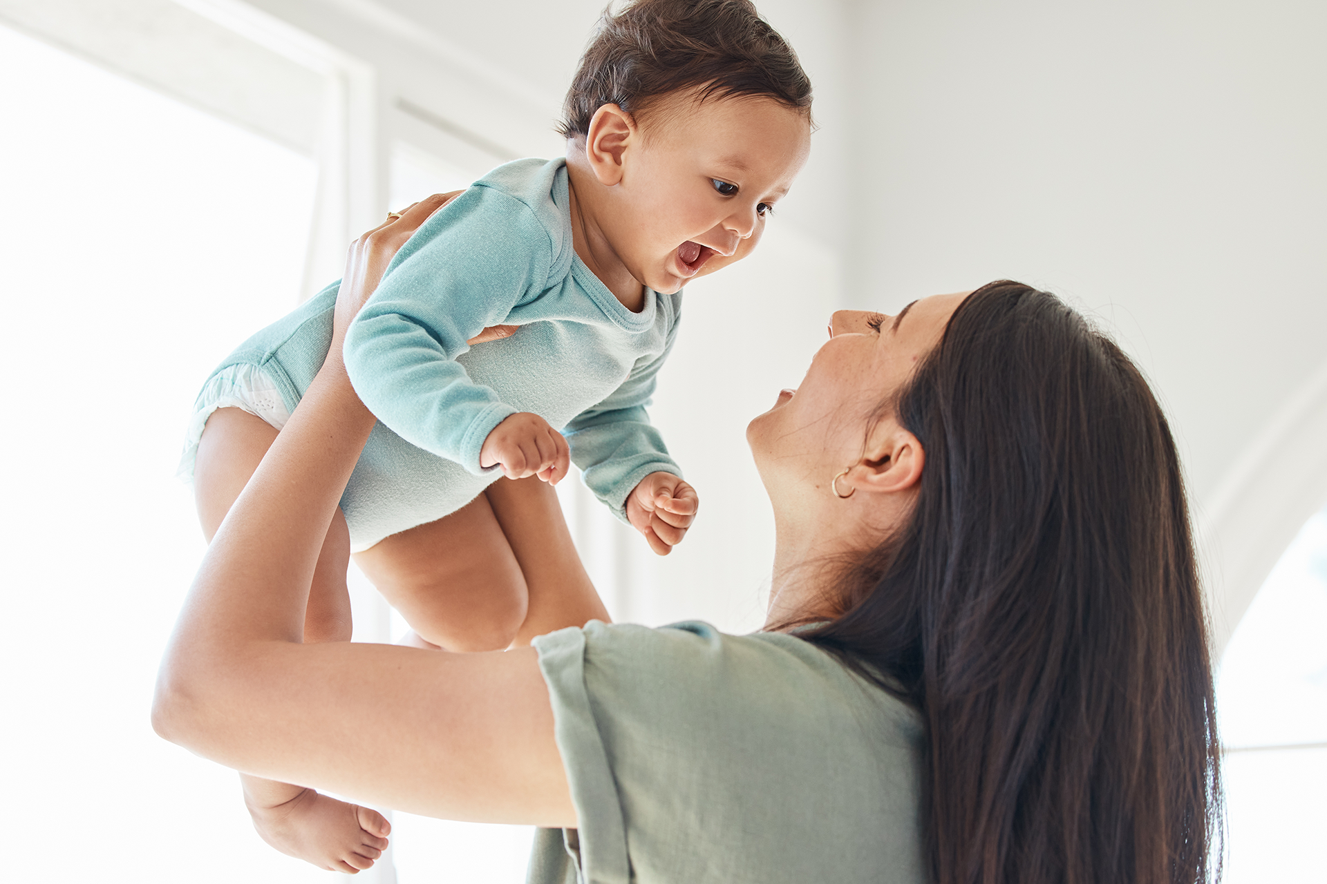 Bebé sonriendo mientras su mamá lo carga.