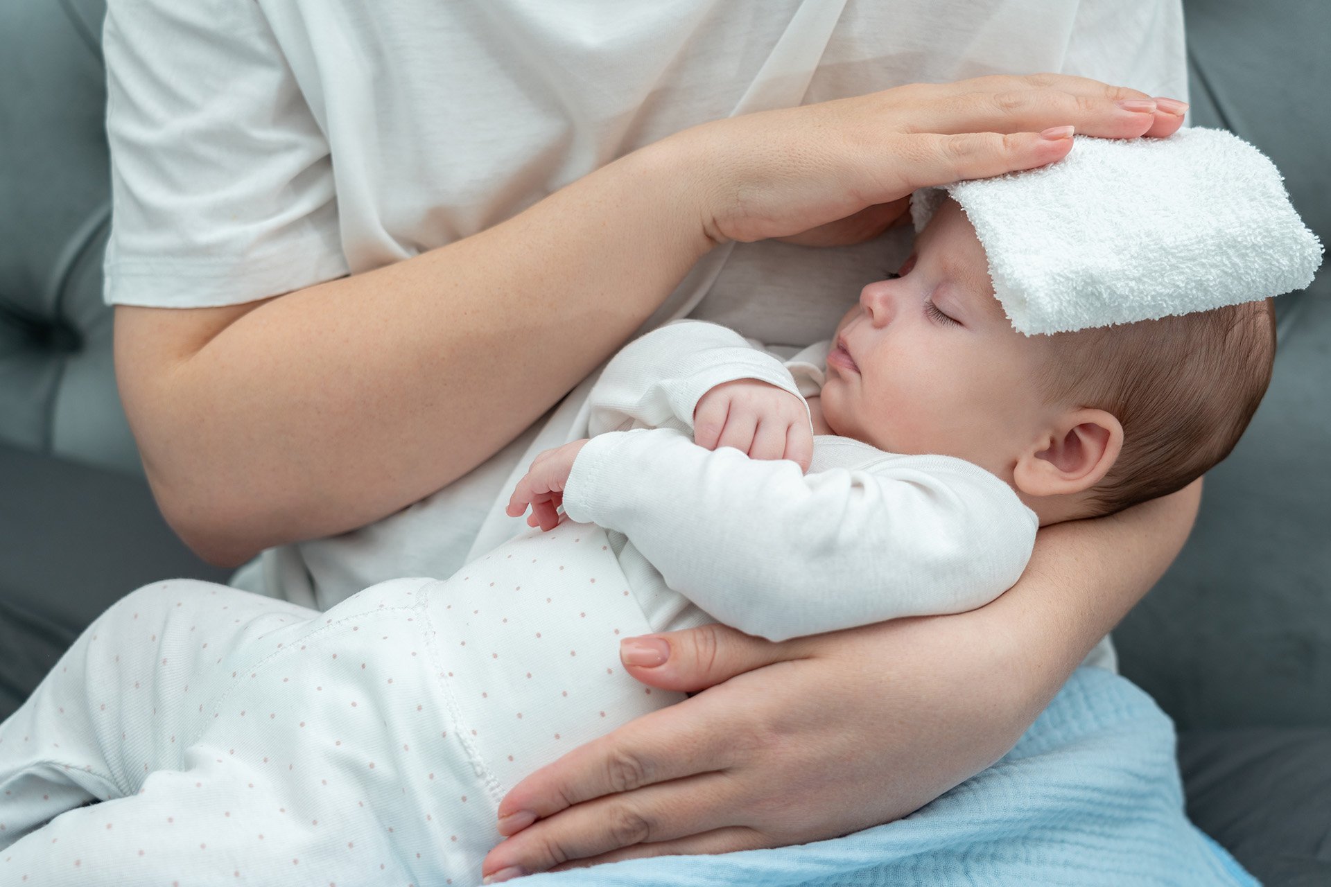 Mamá poniéndole compresas en la cabeza a su bebé.