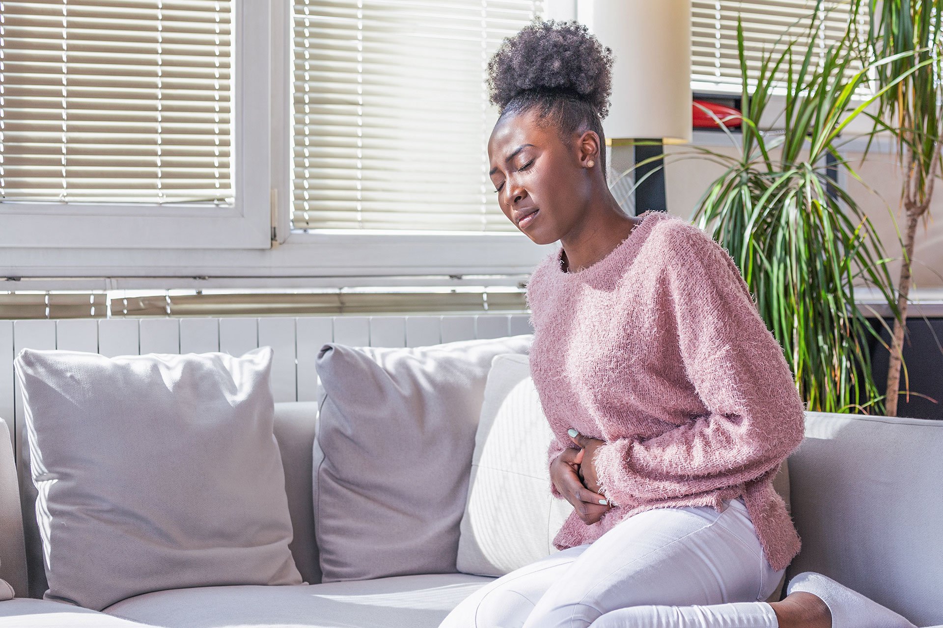 Mujer en el sofá con dolor abdominal
