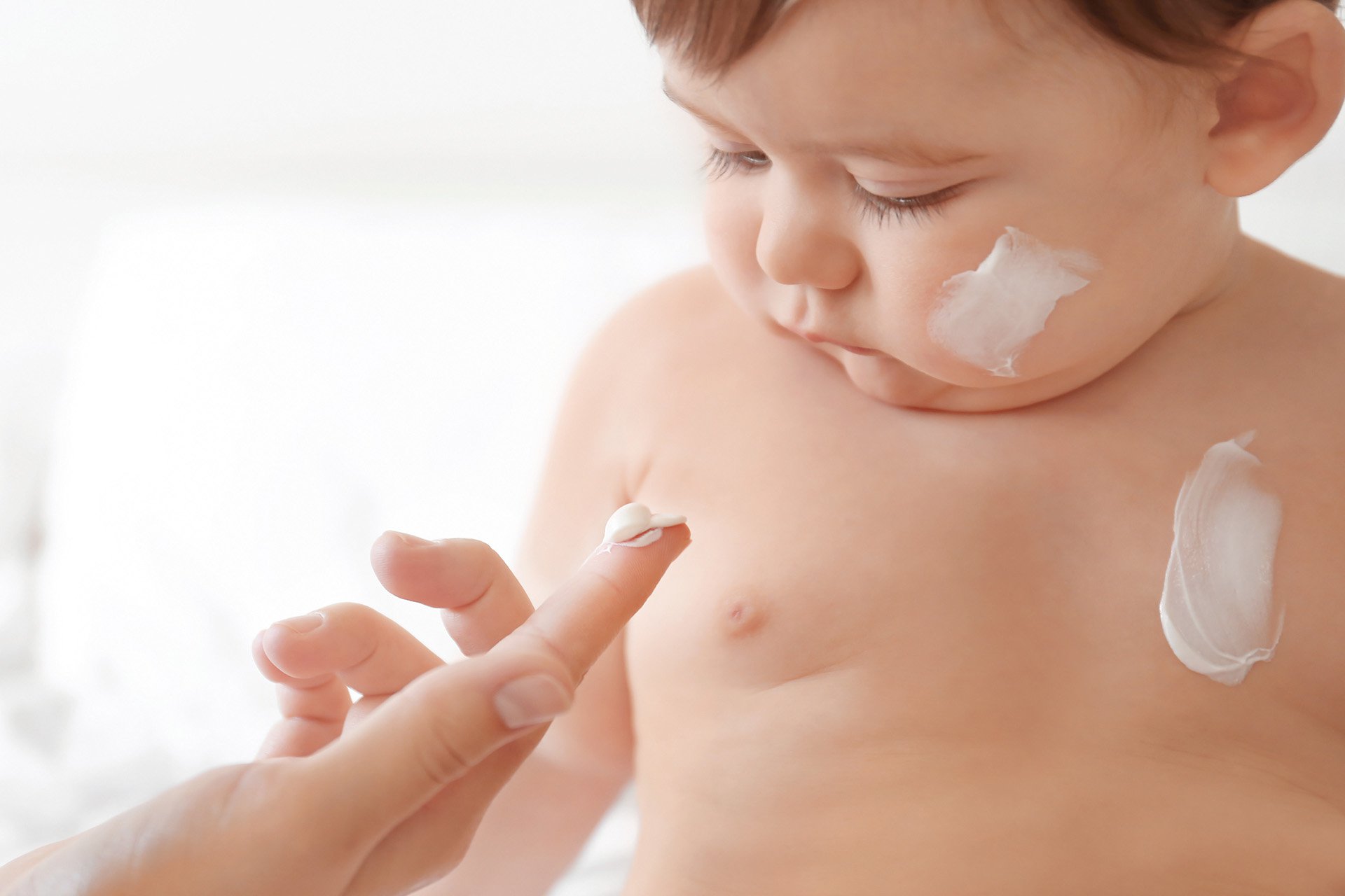Mamá aplicando crema a su bebé en el rostro